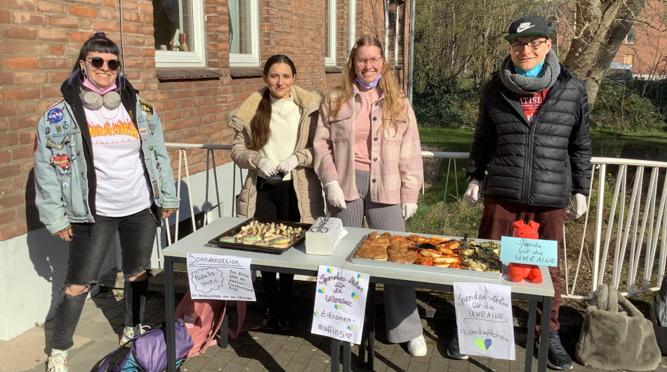 Drei Schülerinnen und ein Schüler des Berufskollegs mit Essen, dass sie gegen Spenden abgeben.