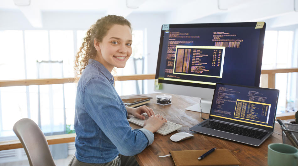 Umschulung zum Fachinformatiker für Anwendungsentwicklung (m/d/w): Eine junge Frau sitzt vor zwei Computerbildschirmen.