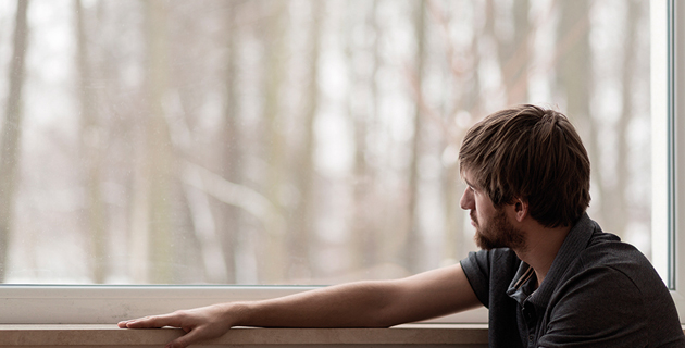 Ein junger Mann mit Autismus blickt aus dem Fenster