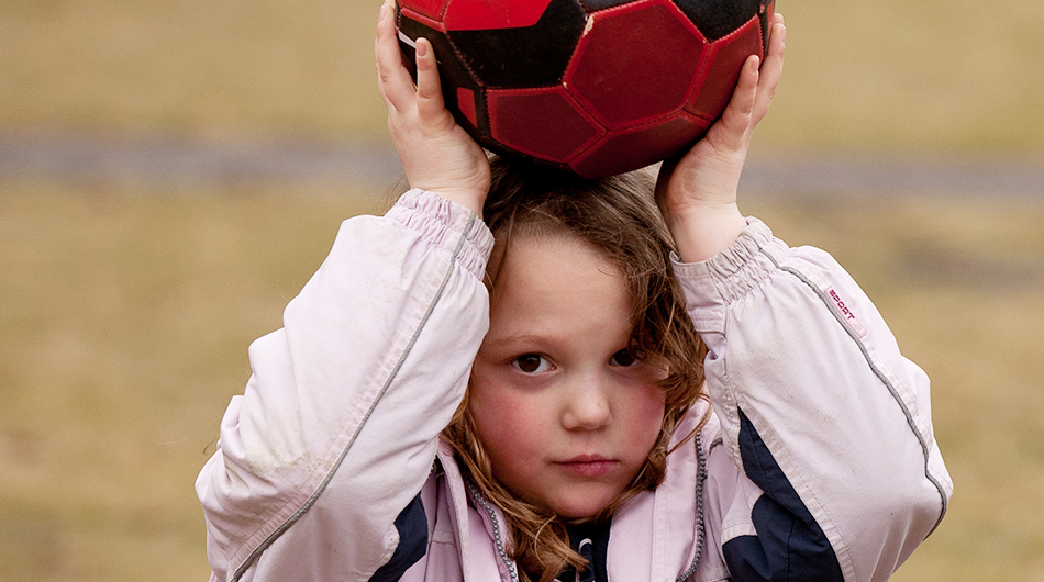 Spende in Köln: Ein junges Mädchen hält einen Ball über dem Kopf.